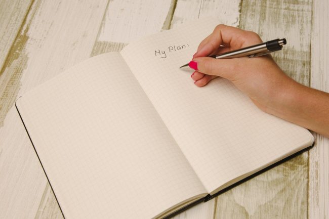 Woman’s hand writing ‘My Plan’ on a notepad
