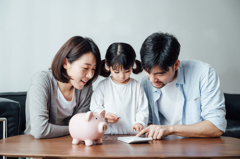 Parents teaching daughter to save money at home