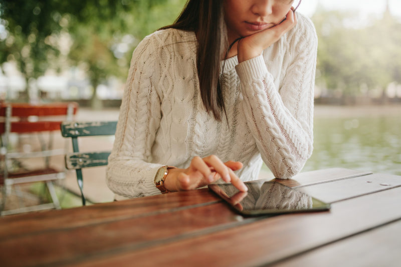 Young woman using digital tablet at outdoor cafe.