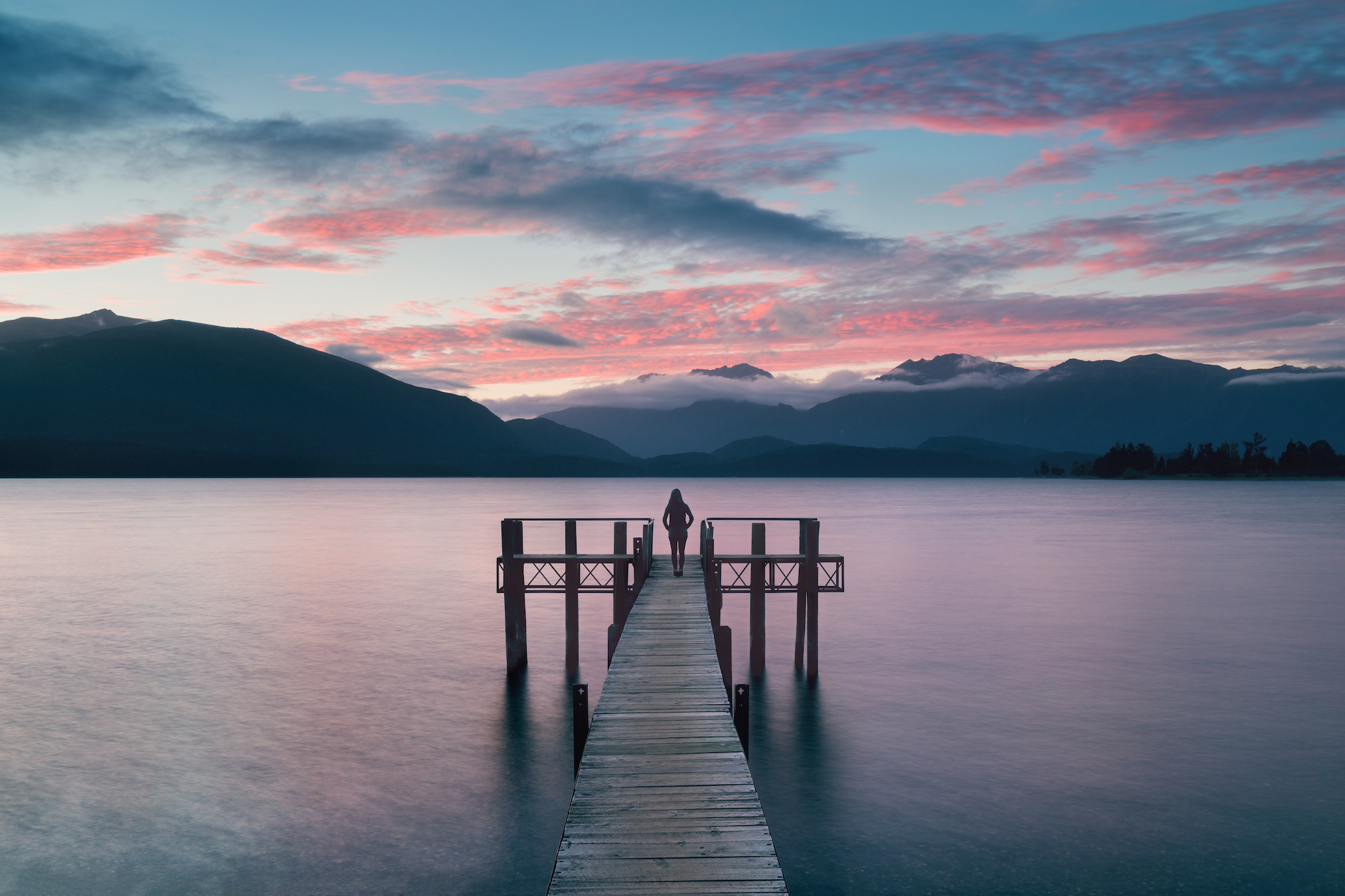 Dock going into the lake at sunset with a pink and blue sky